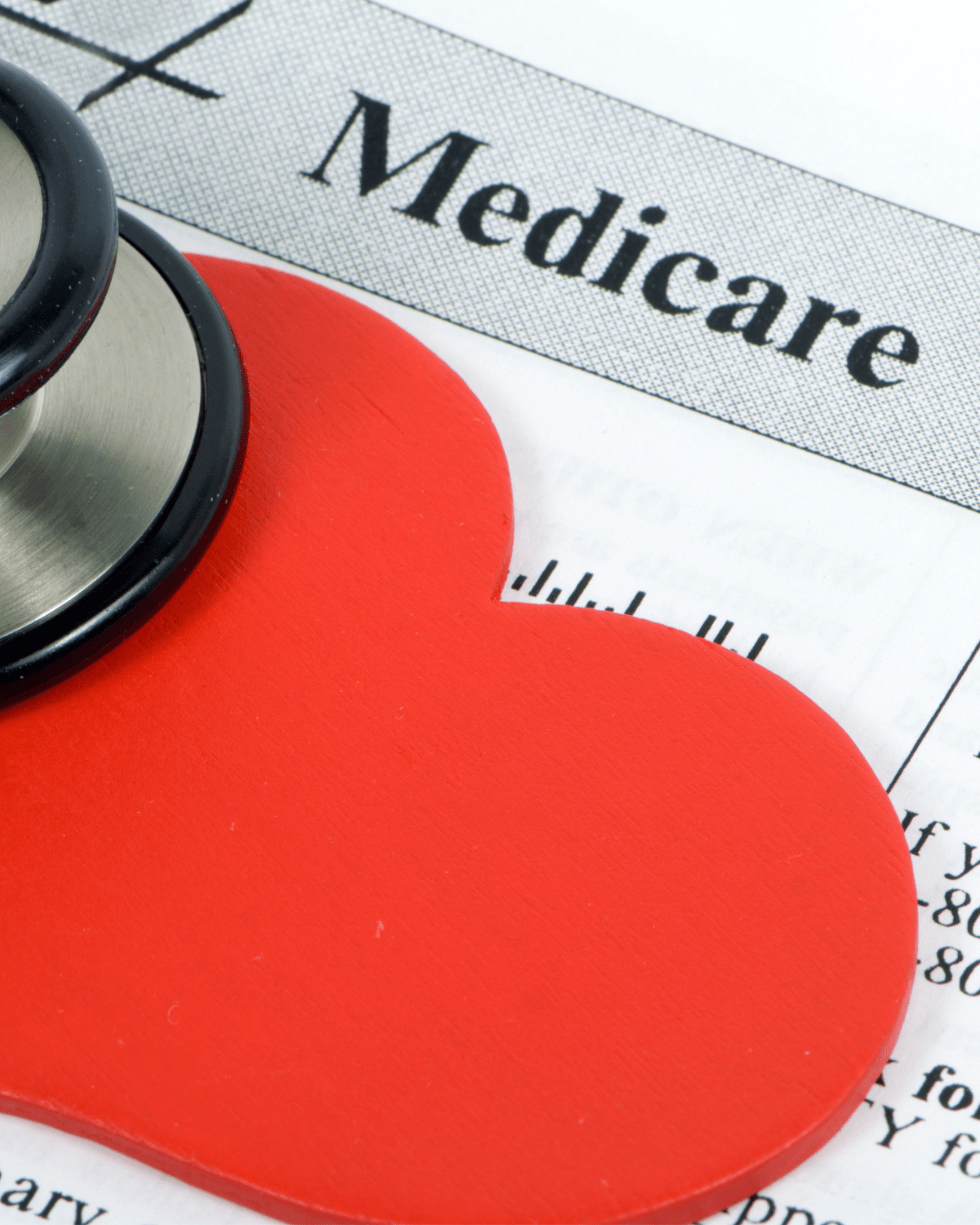Close-up of a stethoscope and red heart shape on a Medicare document, symbolizing healthcare coverage and heart health.